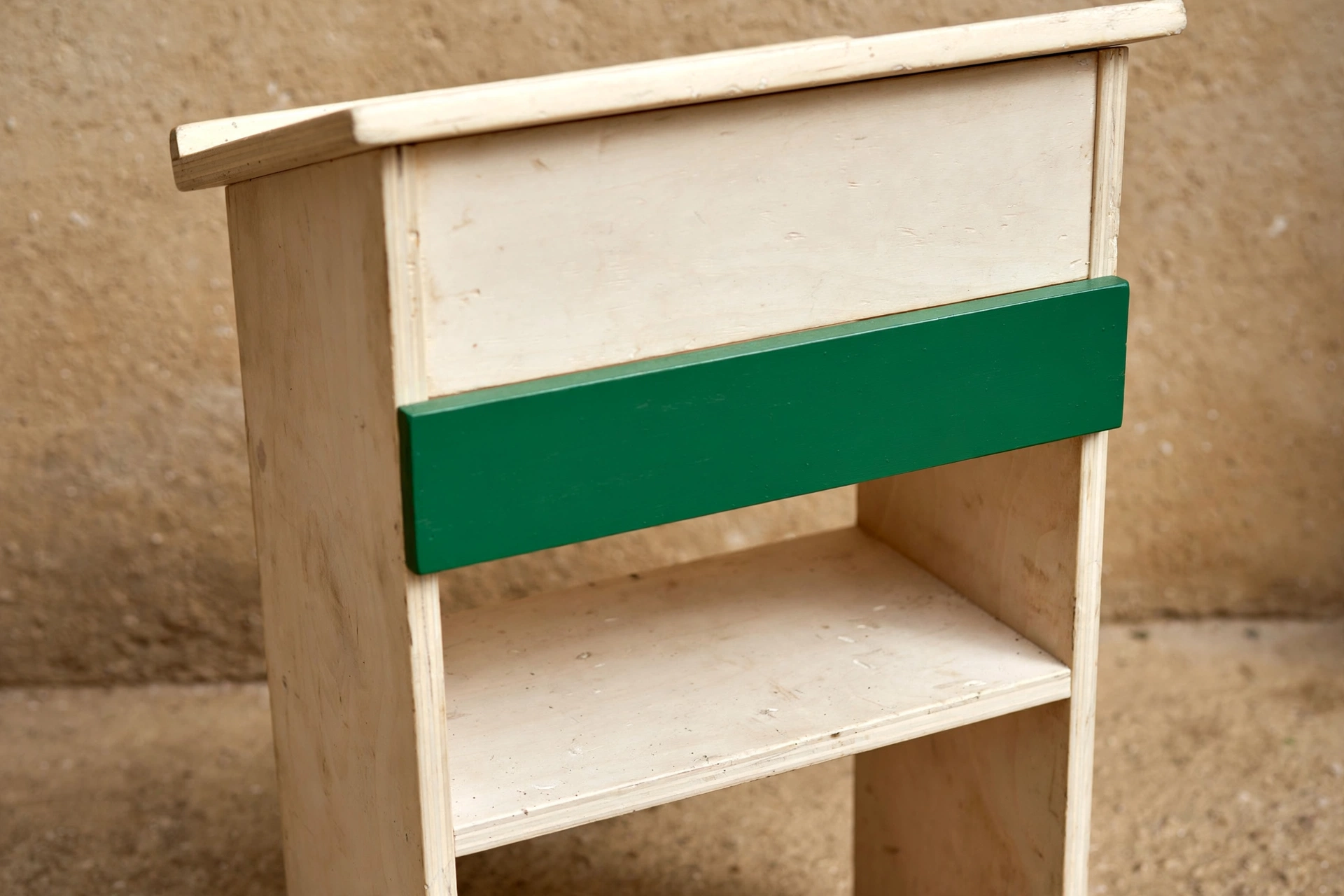 A photograph of a wooden stand with two shelves and a green band across its front.