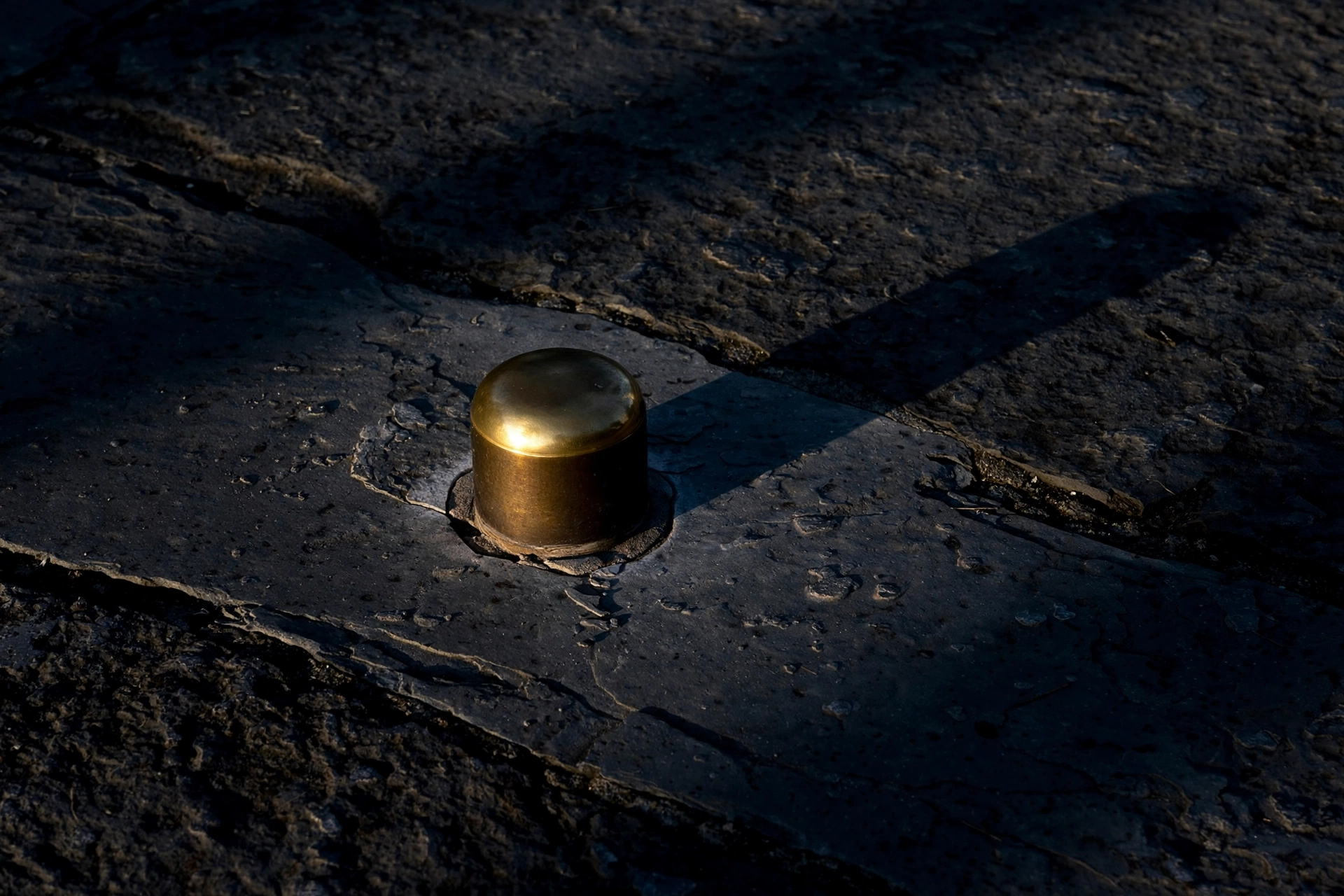 A photograph shows a brass marker on a stone surface.