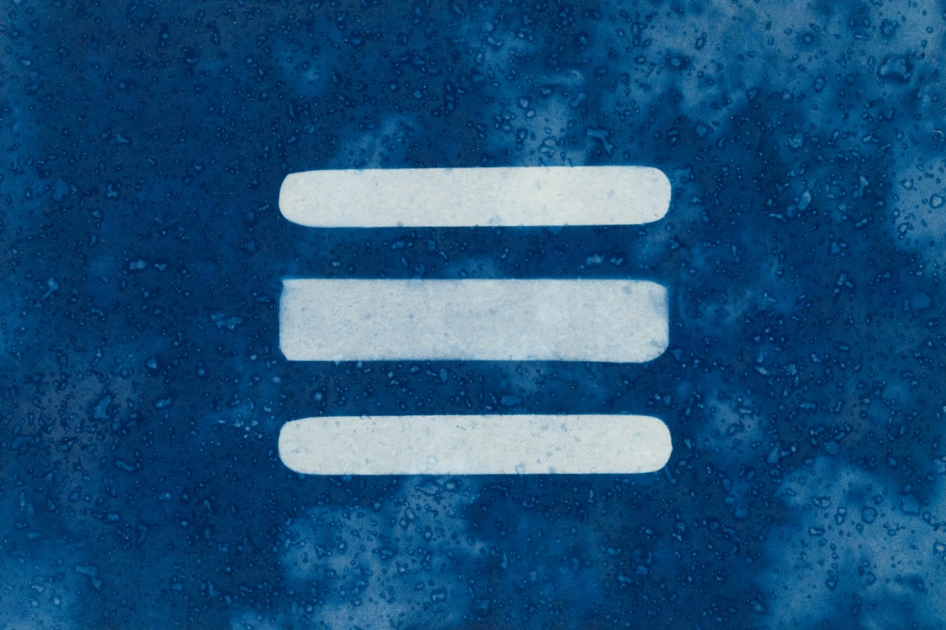 A cyanotype print displays three white horizontal bars on a dark blue background with speckled textures.