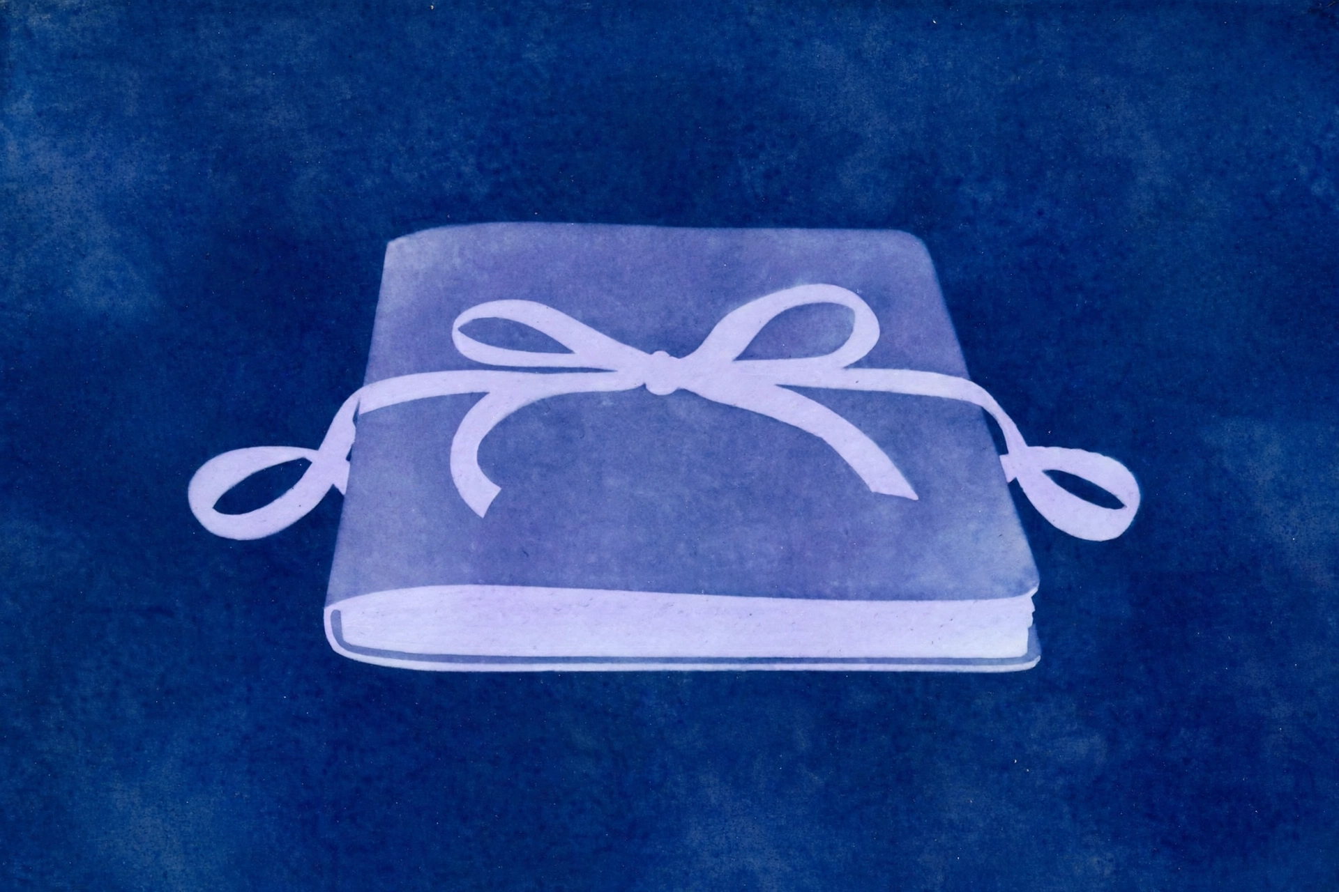 A cyanotype photograph of a closed book wrapped with a white ribbon tied into a bow.