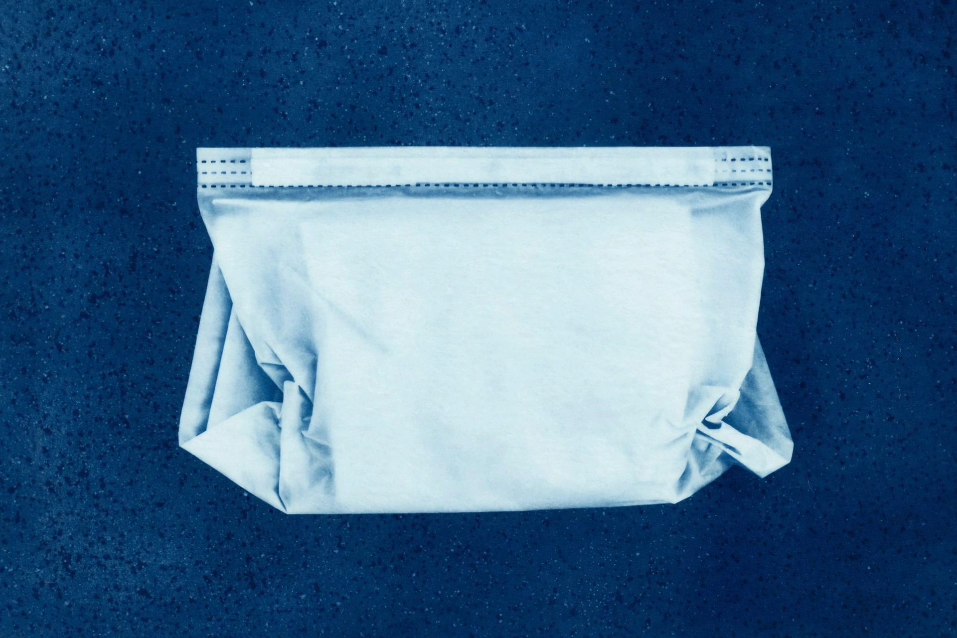 A photograph shows a sealed white bag lying on a dark speckled surface.
