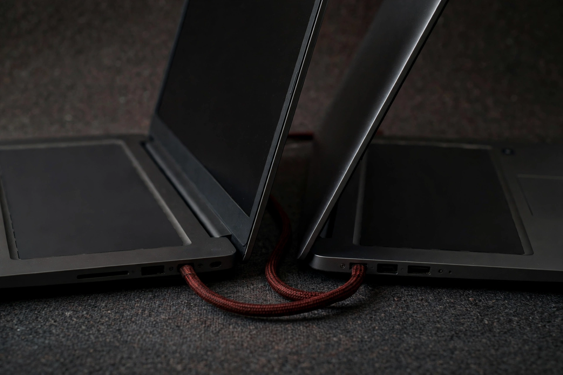 A photograph shows two laptops connected by a braided red cable.