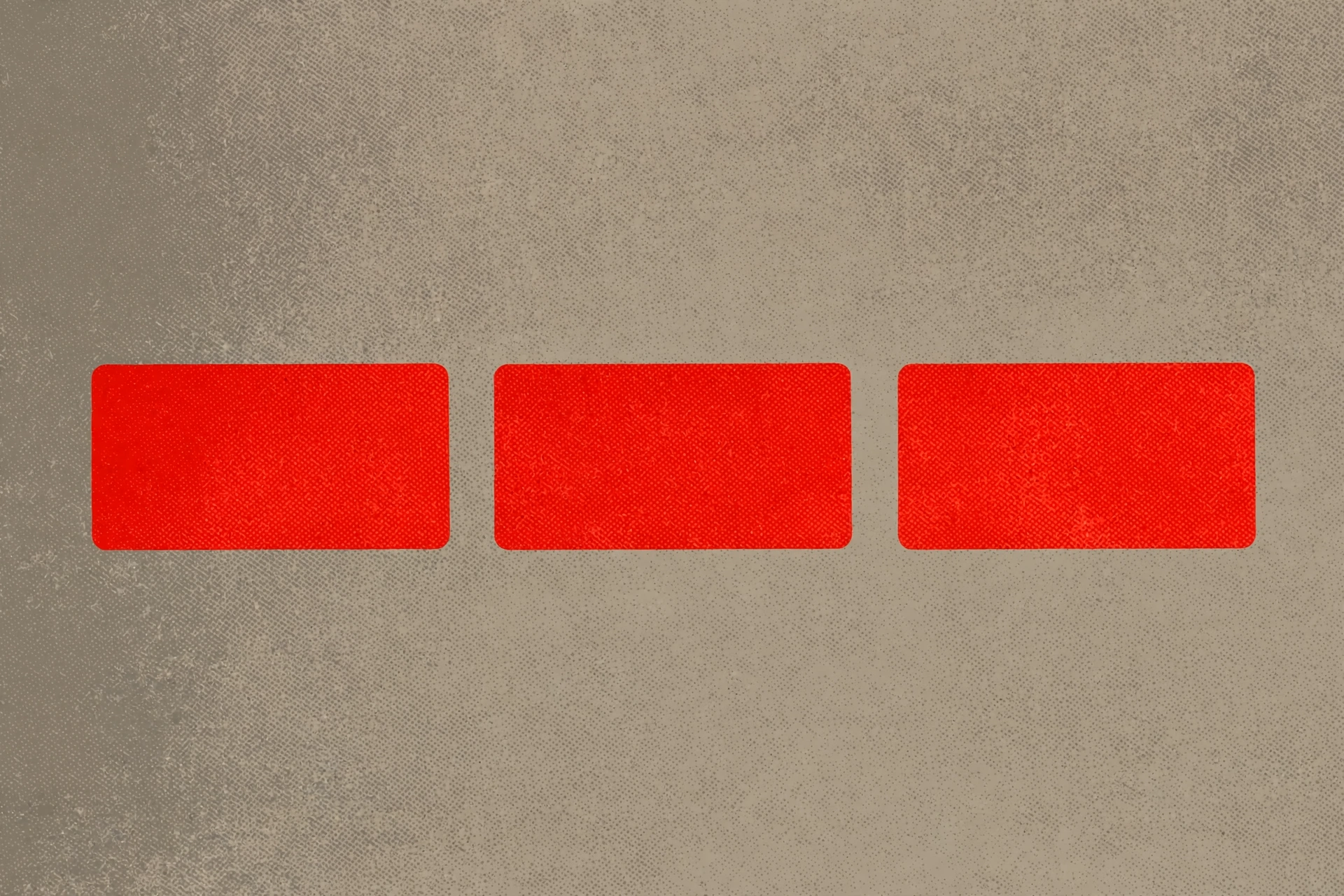 a photograph of three red rectangles against a textured grey background.